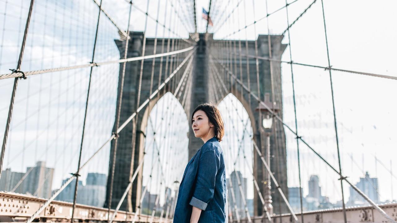 年轻的商人女人望着纽约花车布鲁克林大桥